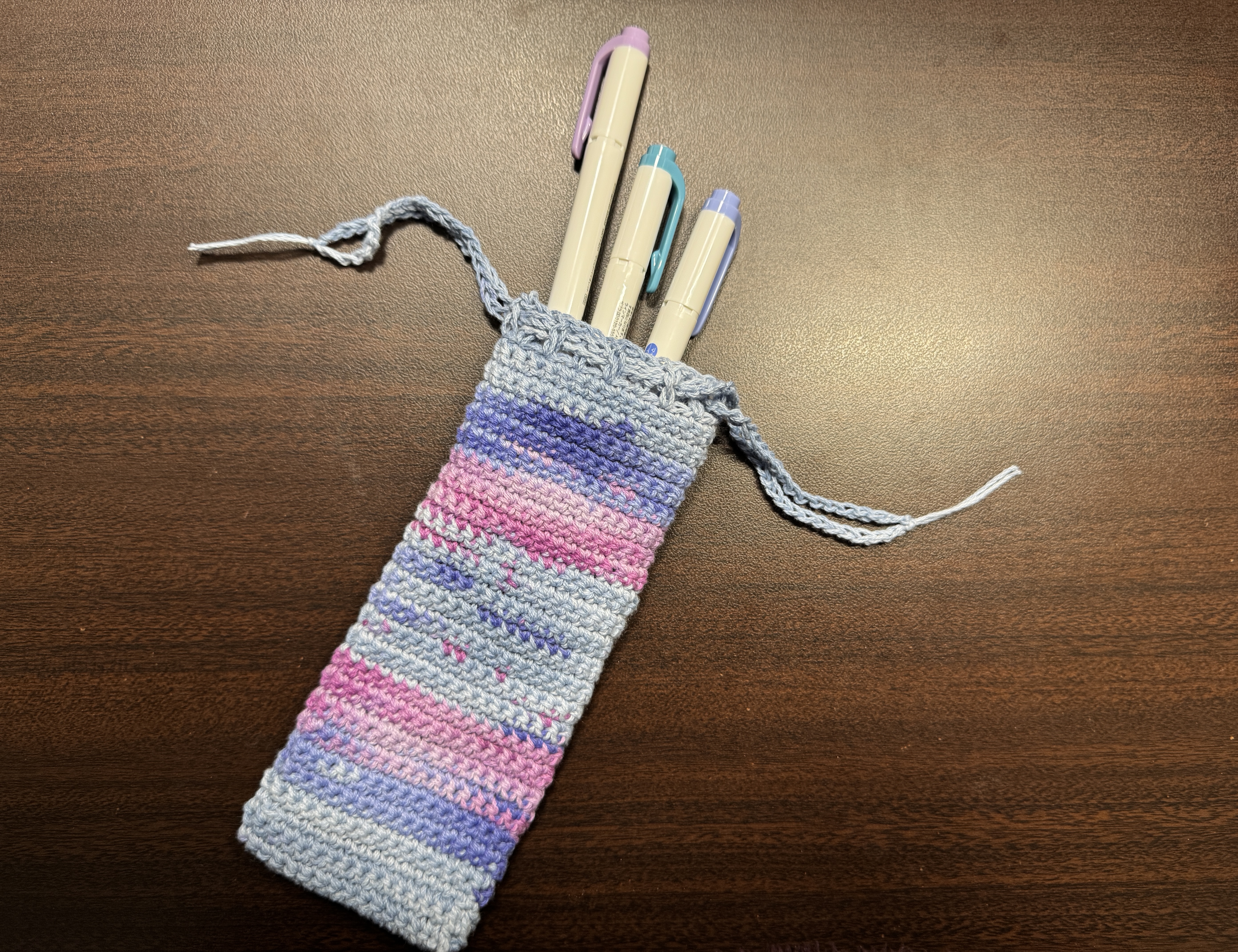 An image of a crocheted pencil case with a variegated yarn